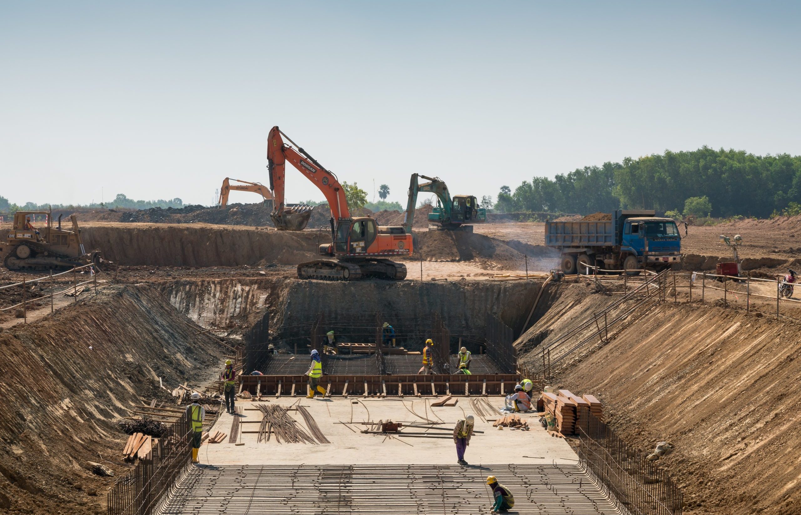 A close shot of heavy machines and construction workers working on a building